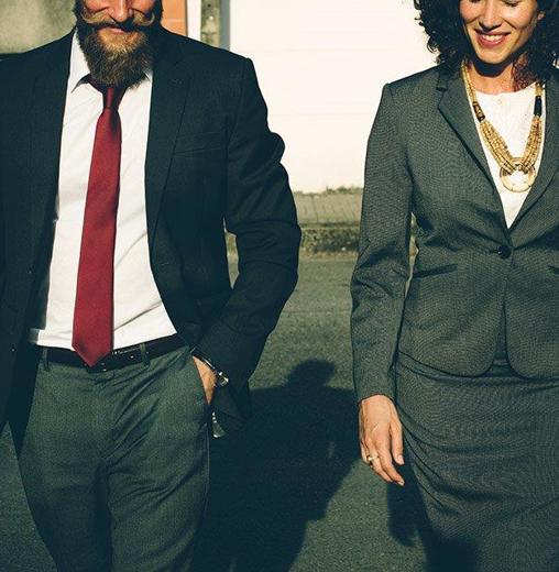 Man in suit holding a briefcase and woman in skirt suit walking